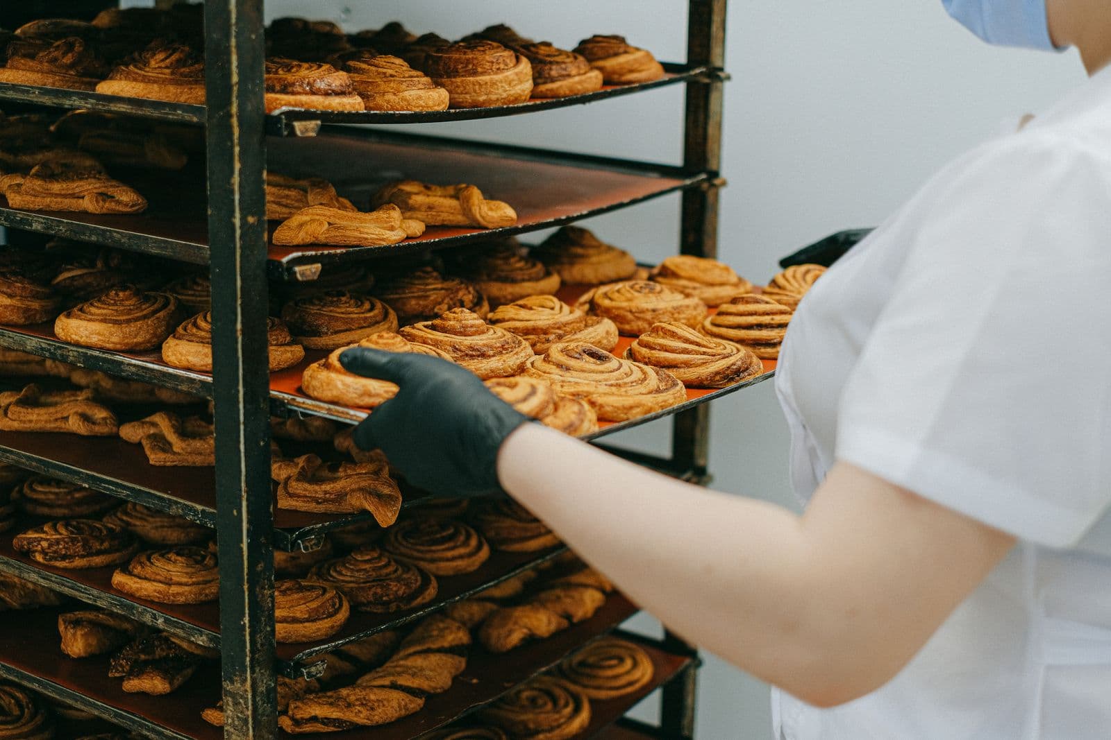 Freshly baked cinnamon rolls being placed on a cooling rack